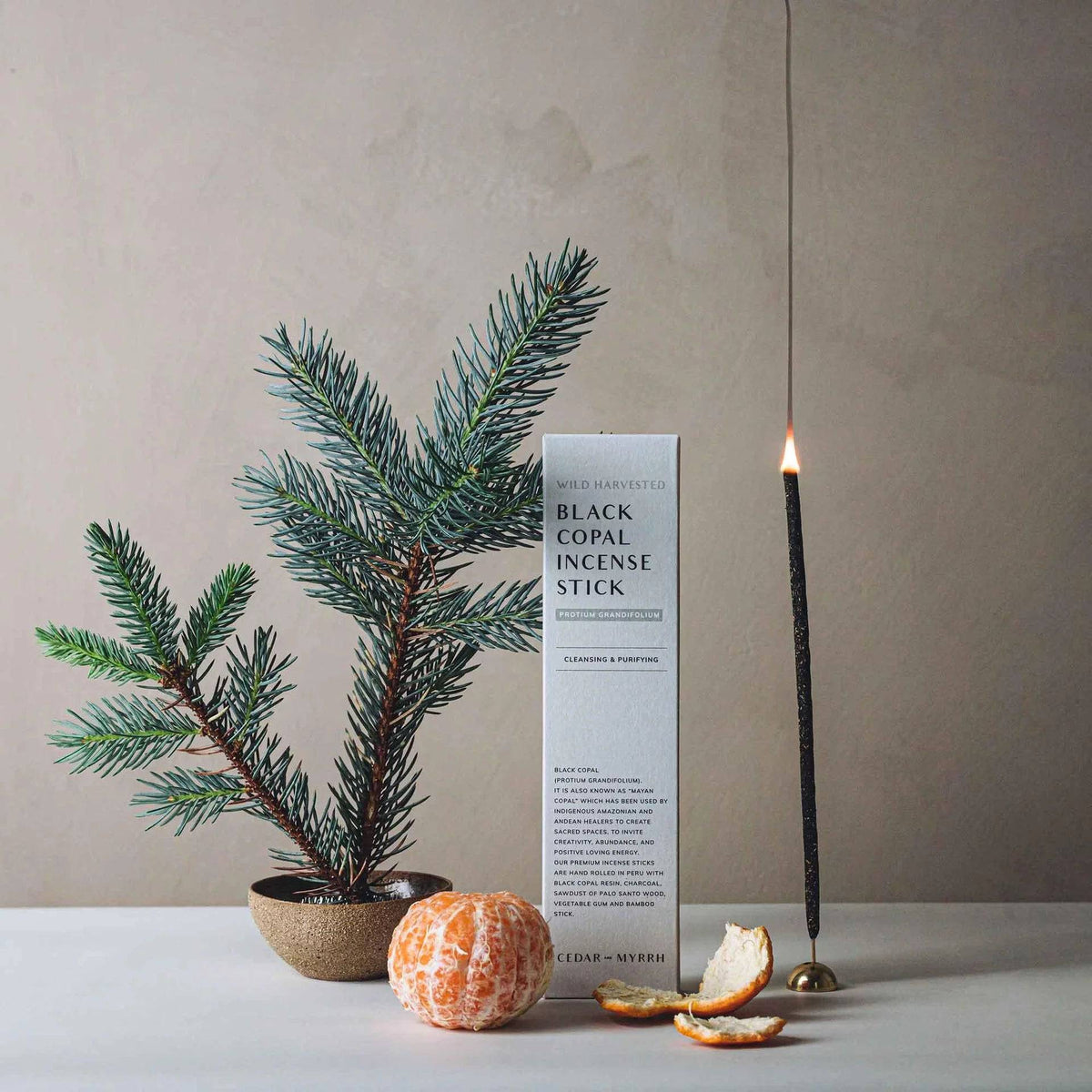 Lit black copal incense stick from Sacred Light Soundbaths and Crystals emitting orange glow, used for aromatic cleansing and meditation.