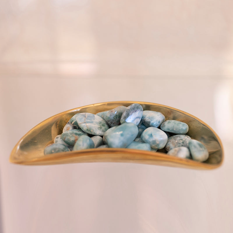Tumbled Larimar stone from Sacred Light Soundbaths and Crystals, showcasing its smooth, blue and white marbled appearance.