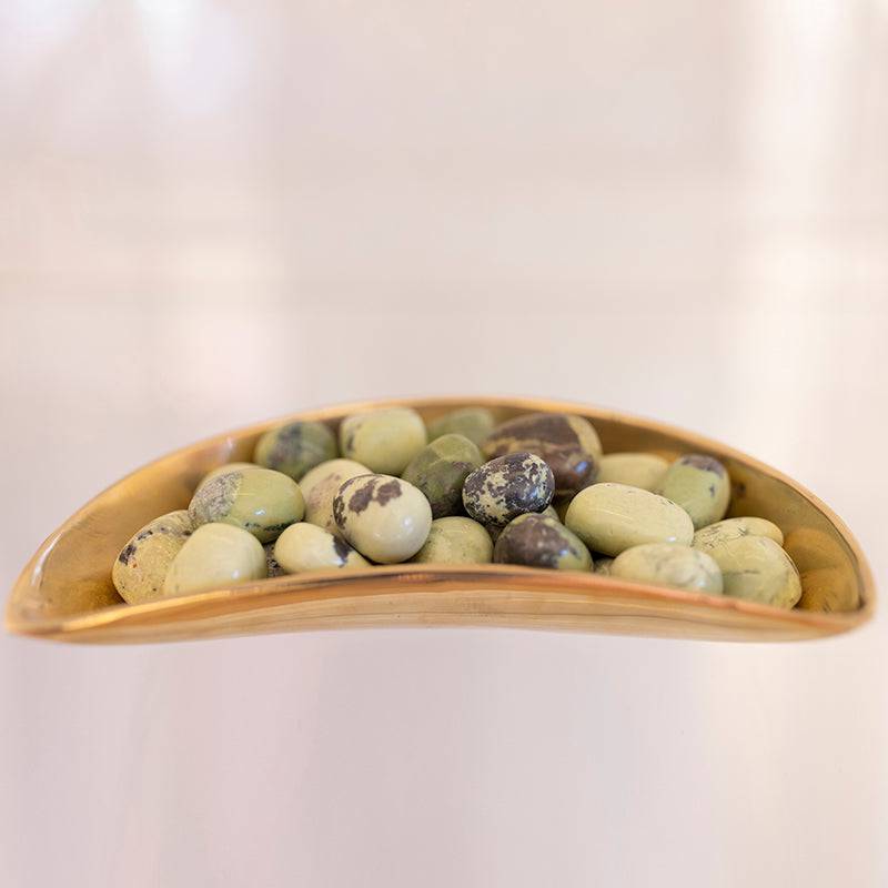 Tumbled Serpentine and Pyrite stones from Sacred Light Soundbaths and Crystals, showcasing their green and metallic gold surfaces.