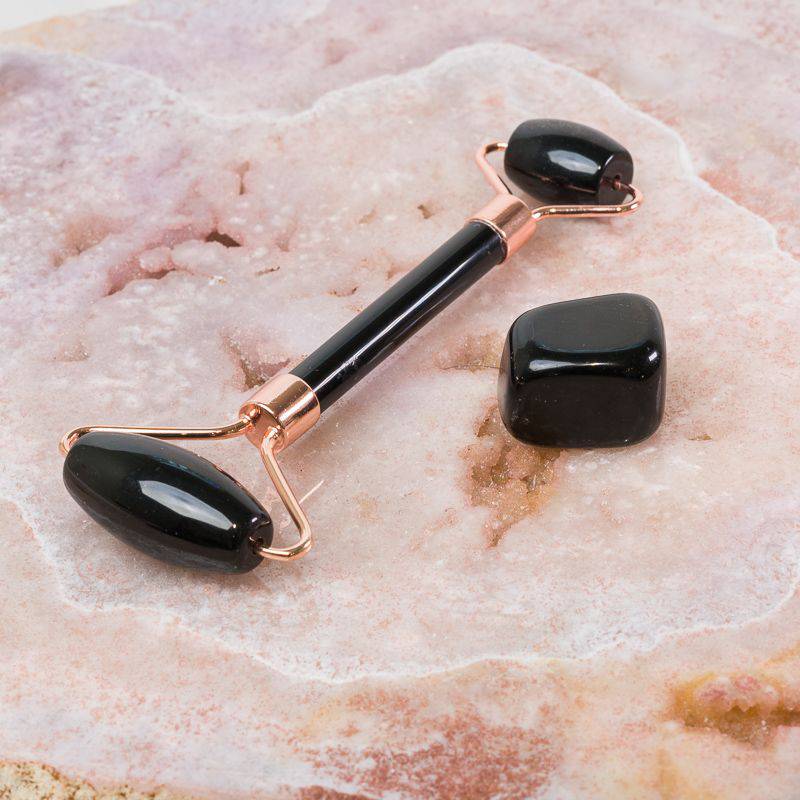 Black Obsidian face massage roller with smooth stones, designed for soothing facial skincare and relaxation.