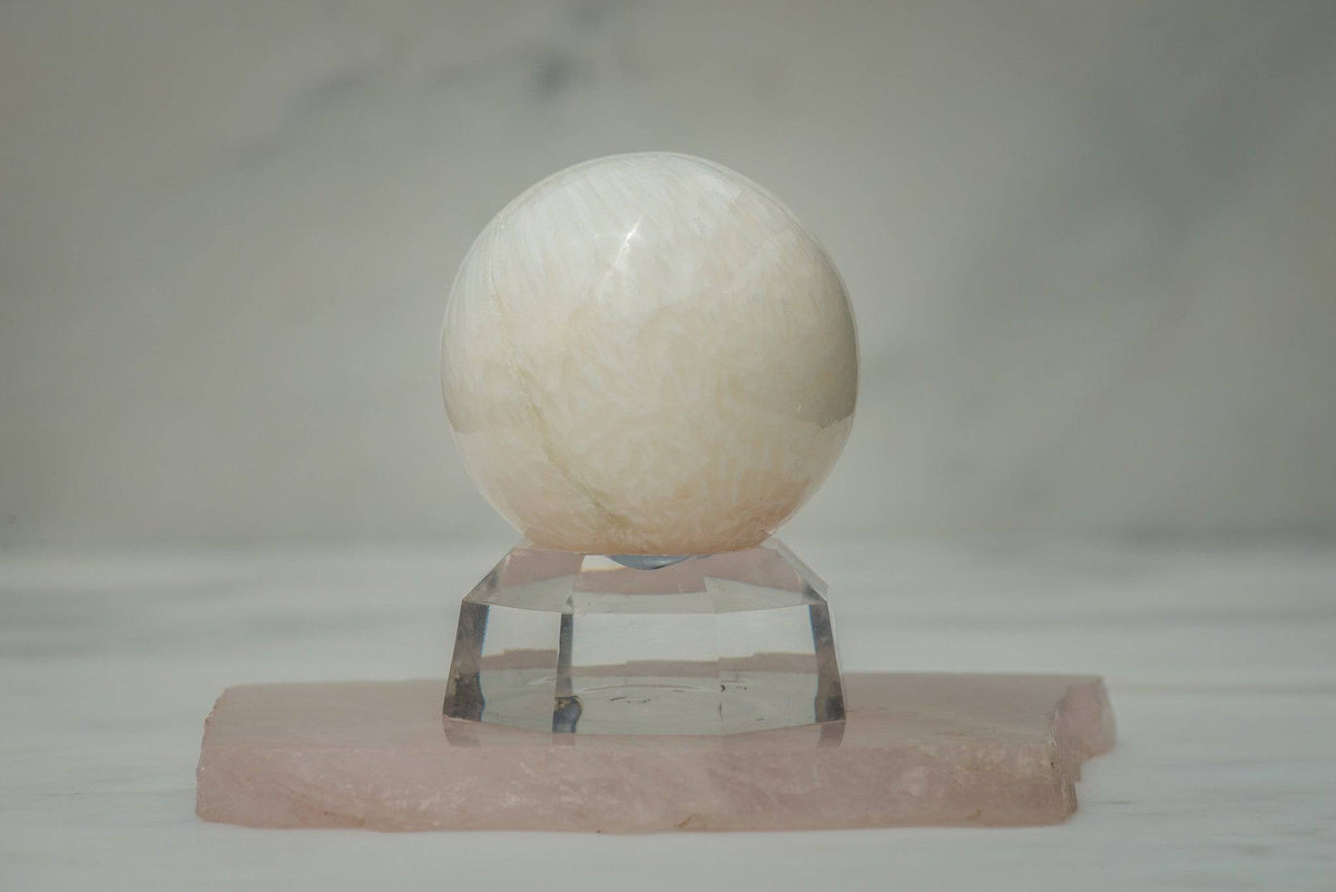 Polished Scolecite sphere from Sacred Light Soundbaths and Crystals, showcasing smooth, translucent stone with gentle natural patterns.