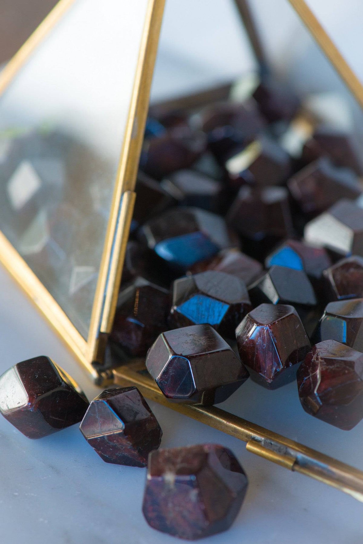 Tumbled faceted Almandine garnet stone from Sacred Light Soundbaths and Crystals, showing deep red color and polished surface.