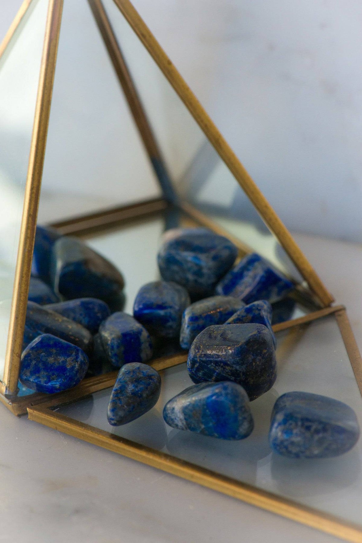 Tumbled Lapis Lazuli stones from Sacred Light Soundbaths and Crystals, showcasing deep blue mineral with gold specks.