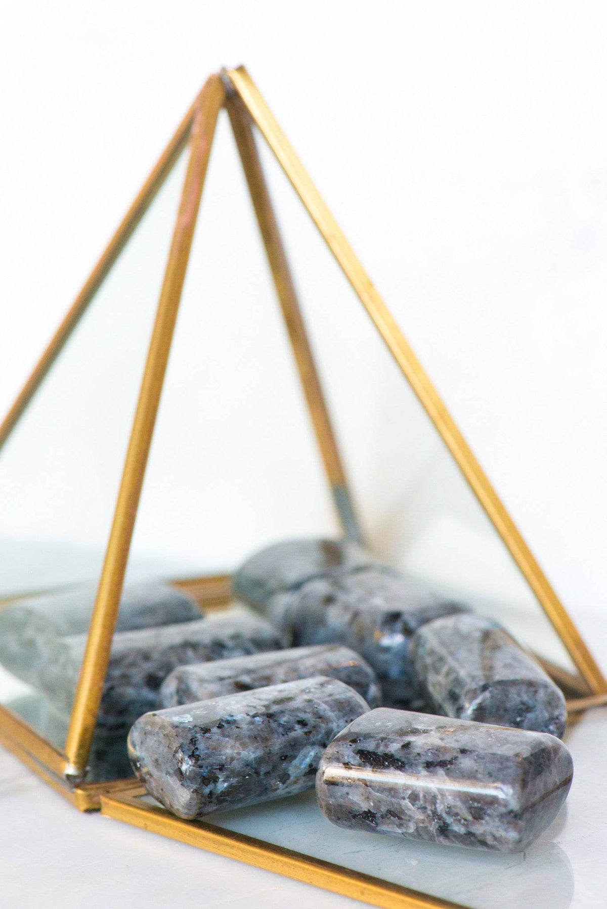 Smooth tumbled Larvikite stone from Sacred Light Soundbaths and Crystals, showcasing its dark, reflective surface and natural mineral patterns.