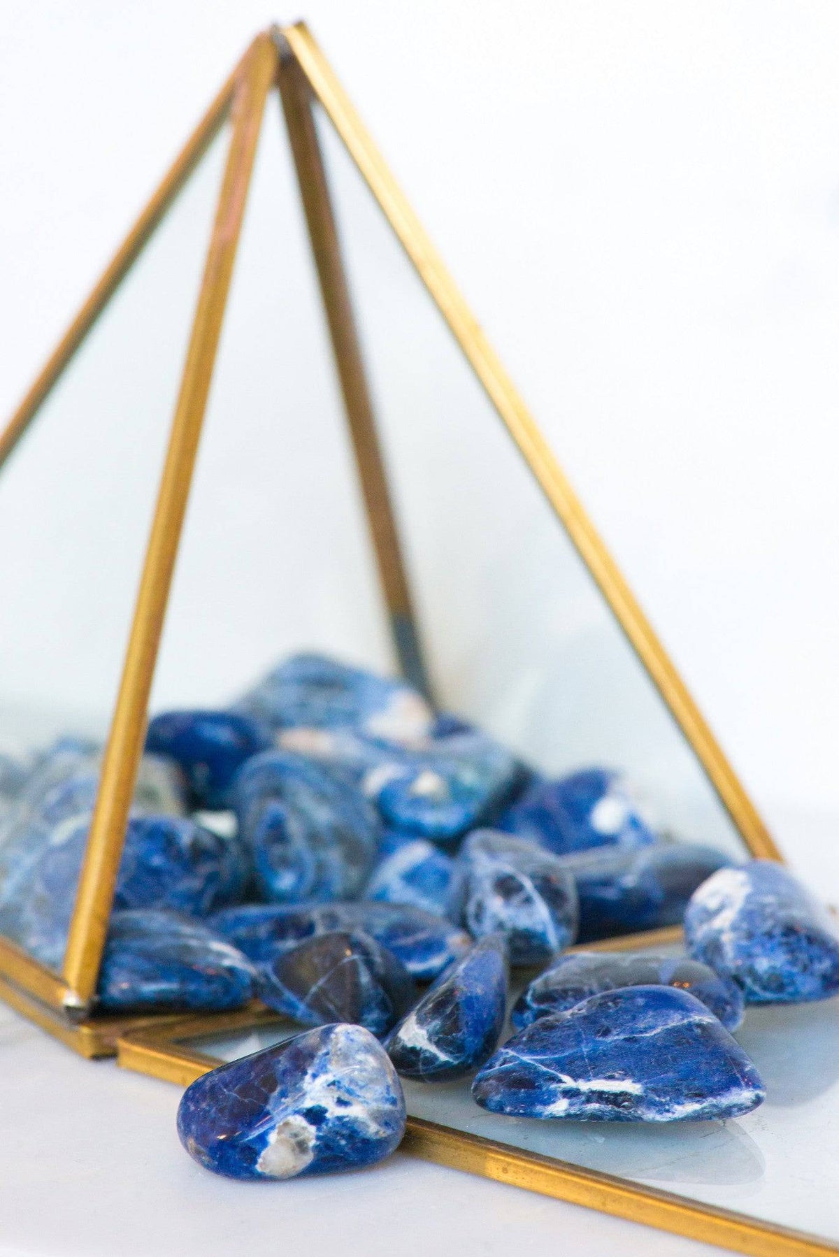 Tumbled Sodalite stone from Sacred Light Soundbaths and Crystals, smooth blue gemstone with white calcite veining.