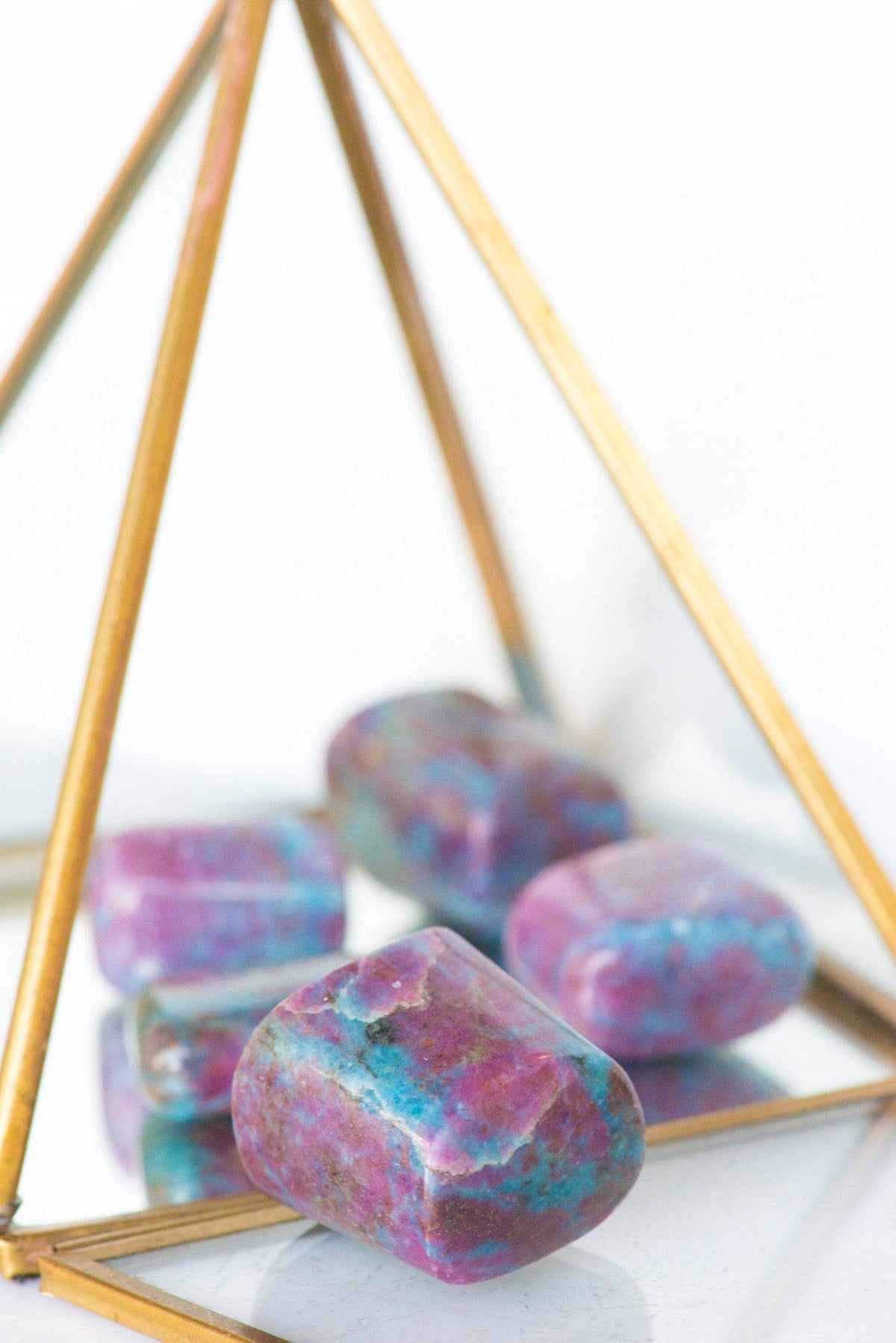 Tumbled ruby and blue kyanite stones from Sacred Light Soundbaths and Crystals displayed on a neutral background.