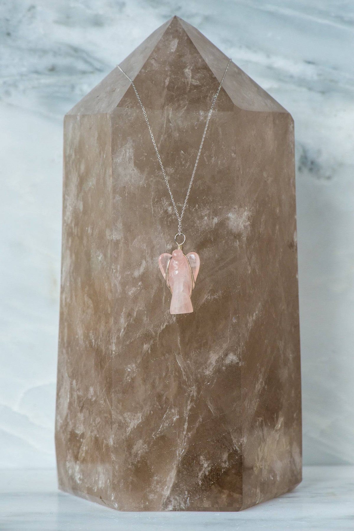 Wire wrapped rose quartz angel necklace featuring a delicate crystal pendant, crafted by Sacred Light Soundbaths and Crystals.