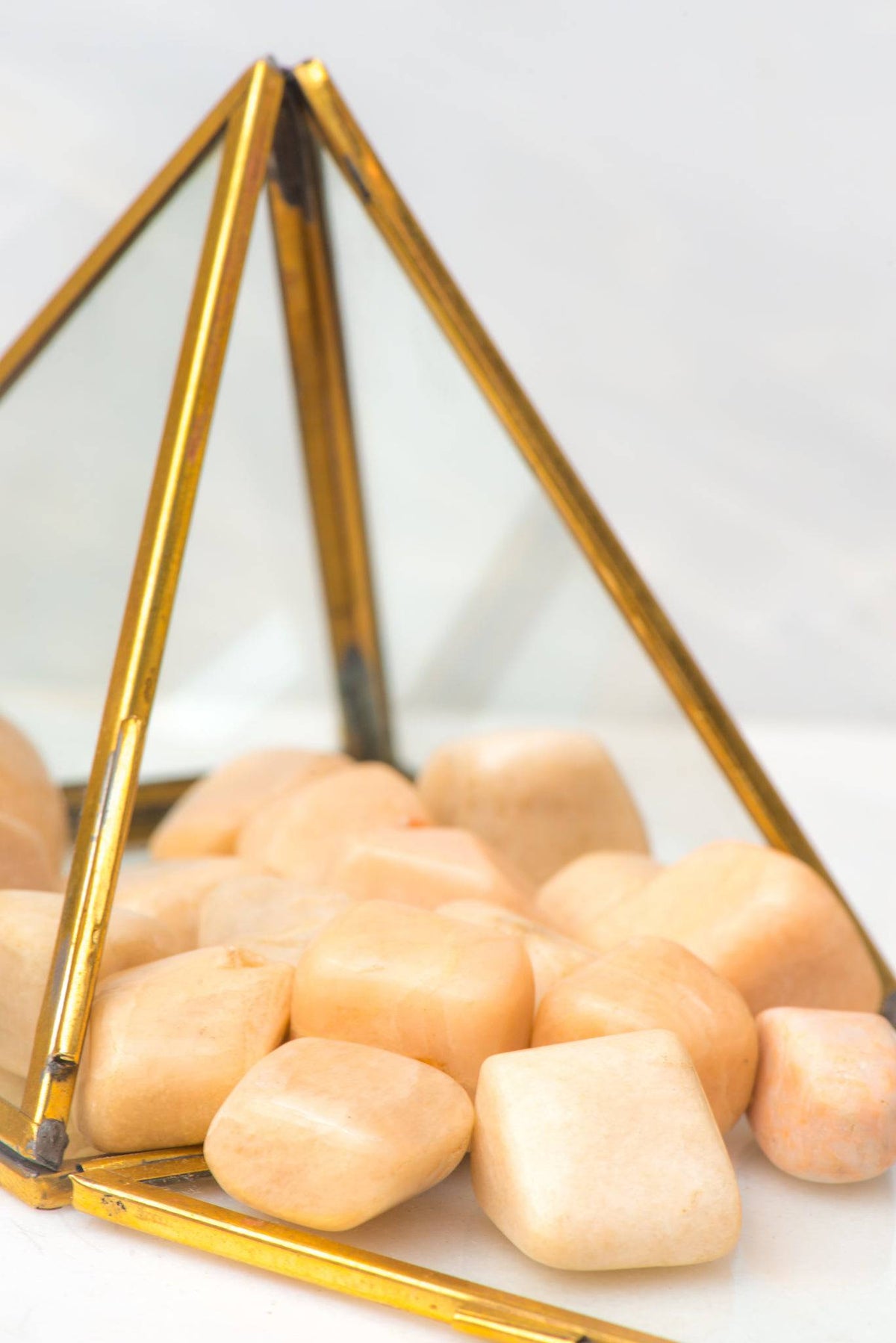 Smooth tumbled peach moonstone crystal stone from Sacred Light Soundbaths and Crystals, showcasing its warm, peachy hue and polished surface.