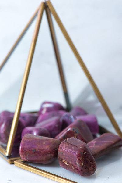 Tumbled red ruby crystal from Sacred Light Soundbaths and Crystals, showcasing its deep red, polished smooth surface.