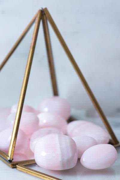Tumbled Mangano Calcite crystal from Sacred Light Soundbaths and Crystals showing smooth, pink-hued mineral with natural surface details.