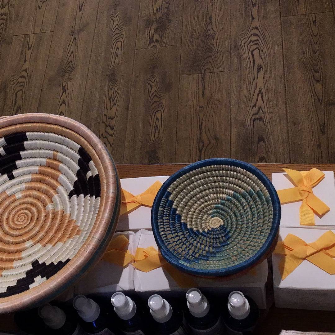 Woven African bowls with intricate patterns and natural fibers, showcased on a wooden surface, from Sacred Light Soundbaths and Crystals.
